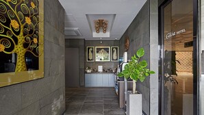 A hotel corridor with a reception desk, a large potted plant, and a modern interior design. - Gloa Hotel (Hwaseong)