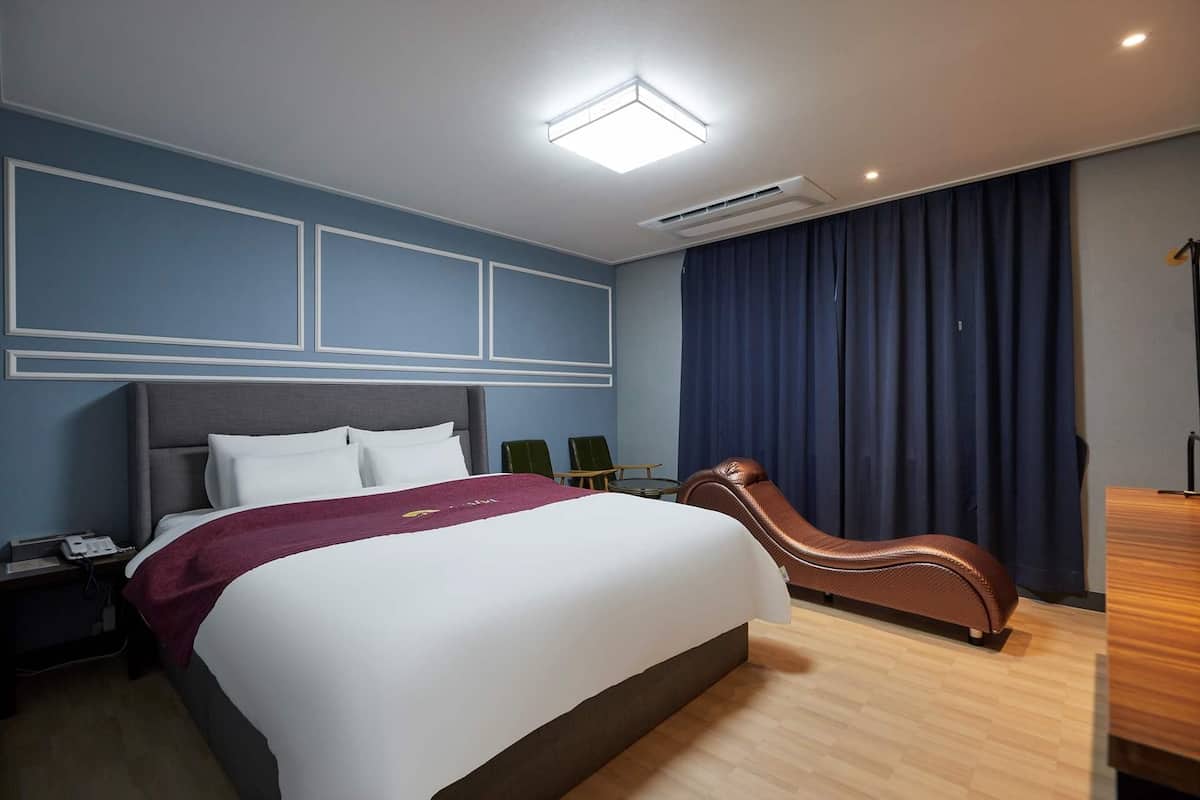 Moderni hotellihuone, jossa on suuri sänky, työpöytä ja tuoli.