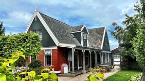 Ein traditionelles Haus mit einem steilen Satteldach, einer Veranda mit Stühlen und einer Schotterauffahrt.