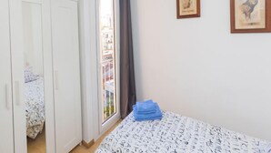 Ein Schlafzimmer mit Bett, Kleiderschrank, einem Fenster mit Aussicht und zwei gerahmten Bildern an der Wand.