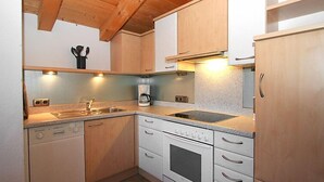 Une cuisine compacte avec des meubles en bois, un four encastré, une machine à café et un évier.