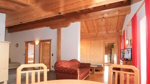 Un intérieur en bois avec une table ronde, deux chaises, un canapé et un téléviseur.