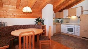 Une cuisine chaleureuse avec des meubles de rangement en bois, une table à manger et un banc.