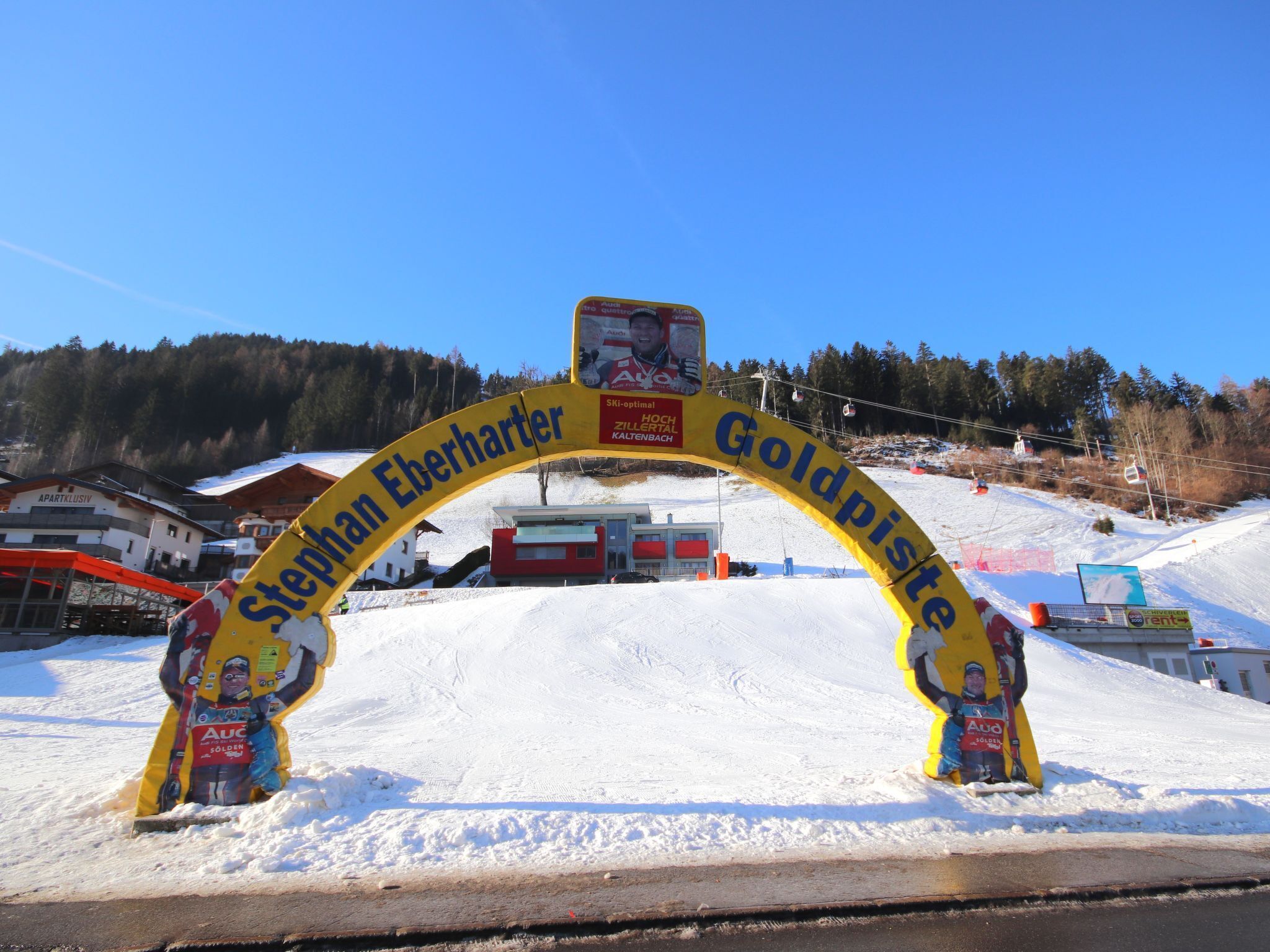 En entré till ett skidområde med en gul båge som visar namnen ”St. Anton Eberharter” och ”Goldpiste”.