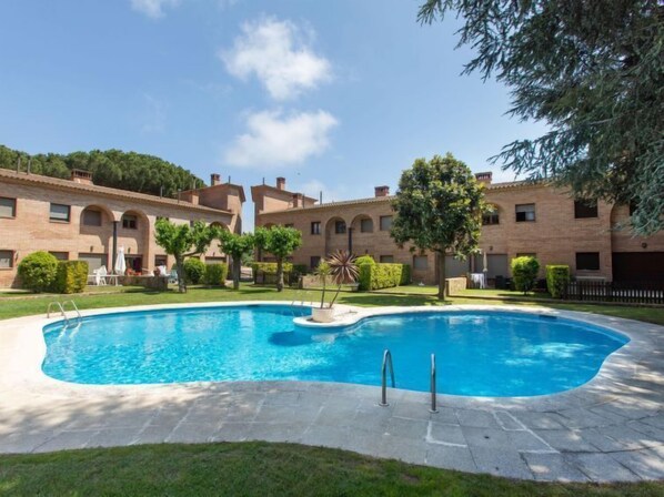 A swimming pool surrounded by a brick building with arched windows and a well-maintained lawn. - Vacation home Club by Interhome (Calonge)