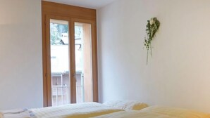 Camera d'albergo con due letti, una porta finestra e un piccolo vaso con una pianta.