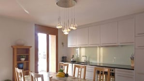 Una cucina con mobili bianchi, un piano di lavoro in vetro e un tavolo da pranzo con sedie.