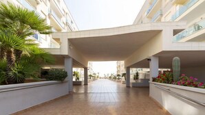 A spacious, modern atrium with tiled flooring, surrounded by balconies and potted plants.