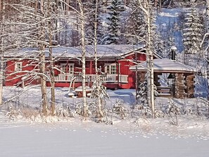 A red cabin with a stone chimney, surrounded by snow-covered trees. - Juurlahti by Interhome (Hartola)