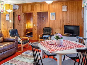 A cozy room with a leather sofa, a dining table with chairs, a television, and a fireplace. - Juurlahti by Interhome (Hartola)
