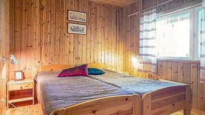 Una stanza con rivestimento in legno, un letto, un comodino e una finestra con tende.