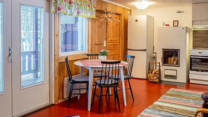 Una cucina accogliente con zona pranzo, pareti in legno e una vistosa tenda per finestra.