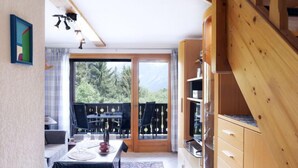 Cocina compacta con comedor, armarios de madera y vistas al exterior.