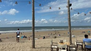A beach with string lights, wooden poles, and beachgoers. - Tapuit 6 by Interhome (Noordwijk)