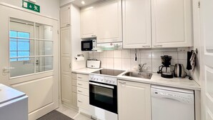 Uma cozinha moderna com armários brancos, micro-ondas, fogão, lava-louças e máquina de café.