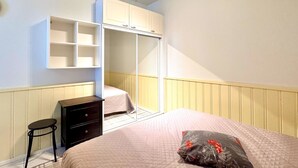 Um quarto com cama, guarda-roupa, escrivaninha e cadeira.