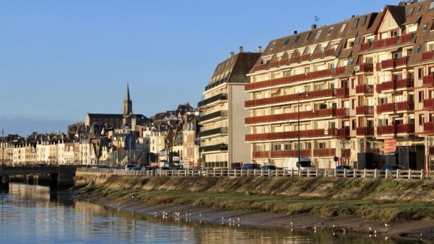 Een hotel aan het water met meerdere verdiepingen, balkons en uitzicht op de rivier.