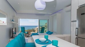 A modern hotel room with a balcony, a dining area with a table set for two, and a kitchen area. - Dream View 50m from the beach by Interhome (Albufeira)