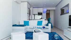 A modern living room with a white sofa, blue cushions, a glass coffee table, and a blue rug. - Dream View 50m from the beach by Interhome (Albufeira)