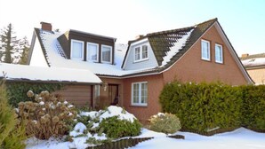 A two-story house with a sloped roof, a garage, and a snow-covered garden. - Sandburg by Interhome (Norddeich)