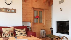 Ein gemütliches Wohnzimmer mit Holztisch, rotem Sofa und Kamin.