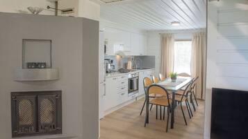 A modern kitchen with white cabinets, a dining area with a table and chairs, and a TV on a stand.