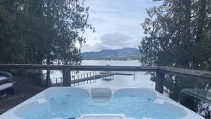 A hot tub with a view of a lake and mountains.