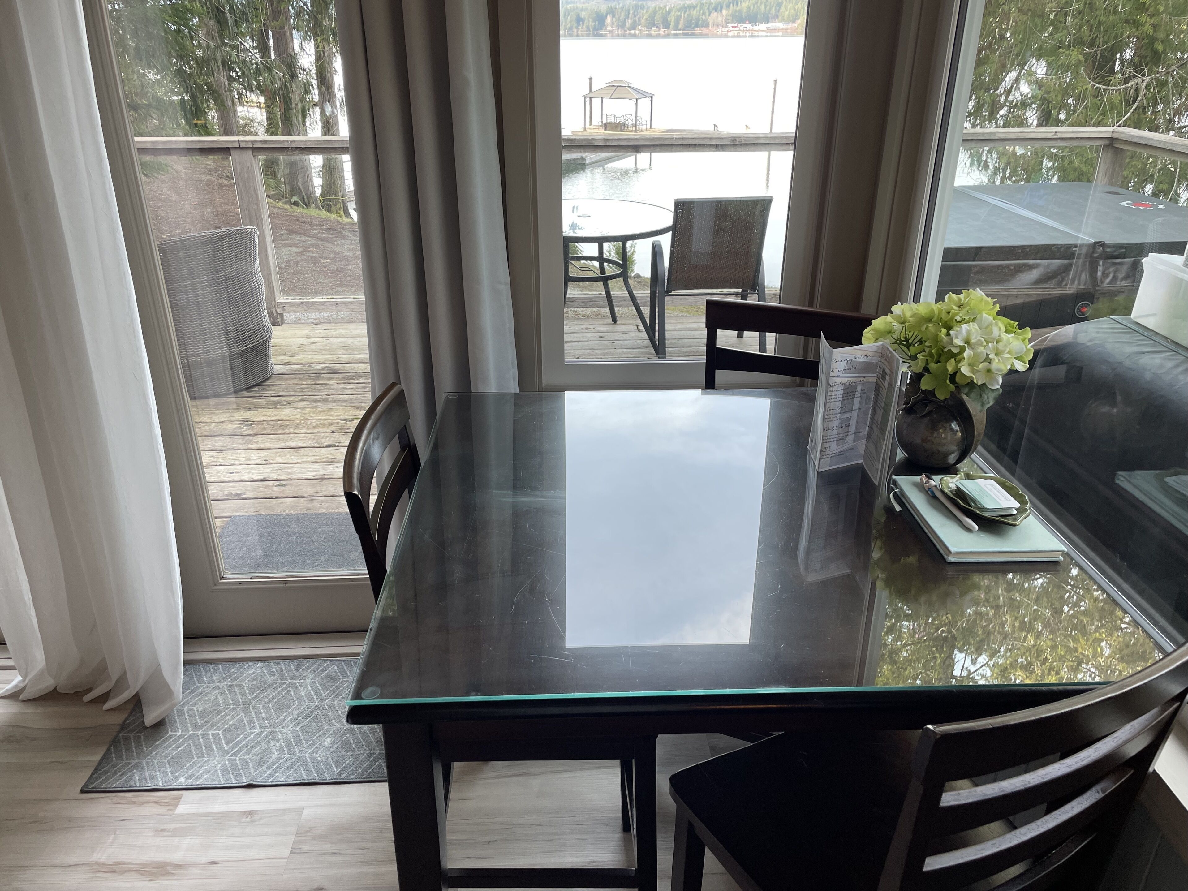 A modern dining area with a glass table, black chairs, and a sofa.