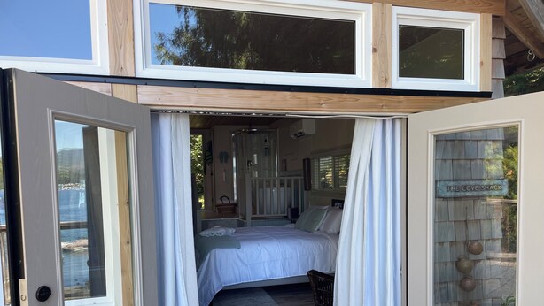 A cozy bedroom with a bed, a small seating area, and a view of the outdoors.