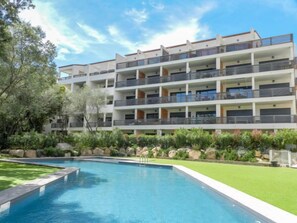 Un hôtel à plusieurs étages doté d’une piscine, entouré d’un espace paysager verdoyant et de rochers.