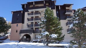 A multi-story hotel with balconies, snow-covered trees, and a clear sky. - Astragale 412 A by Interhome (Les Menuires)
