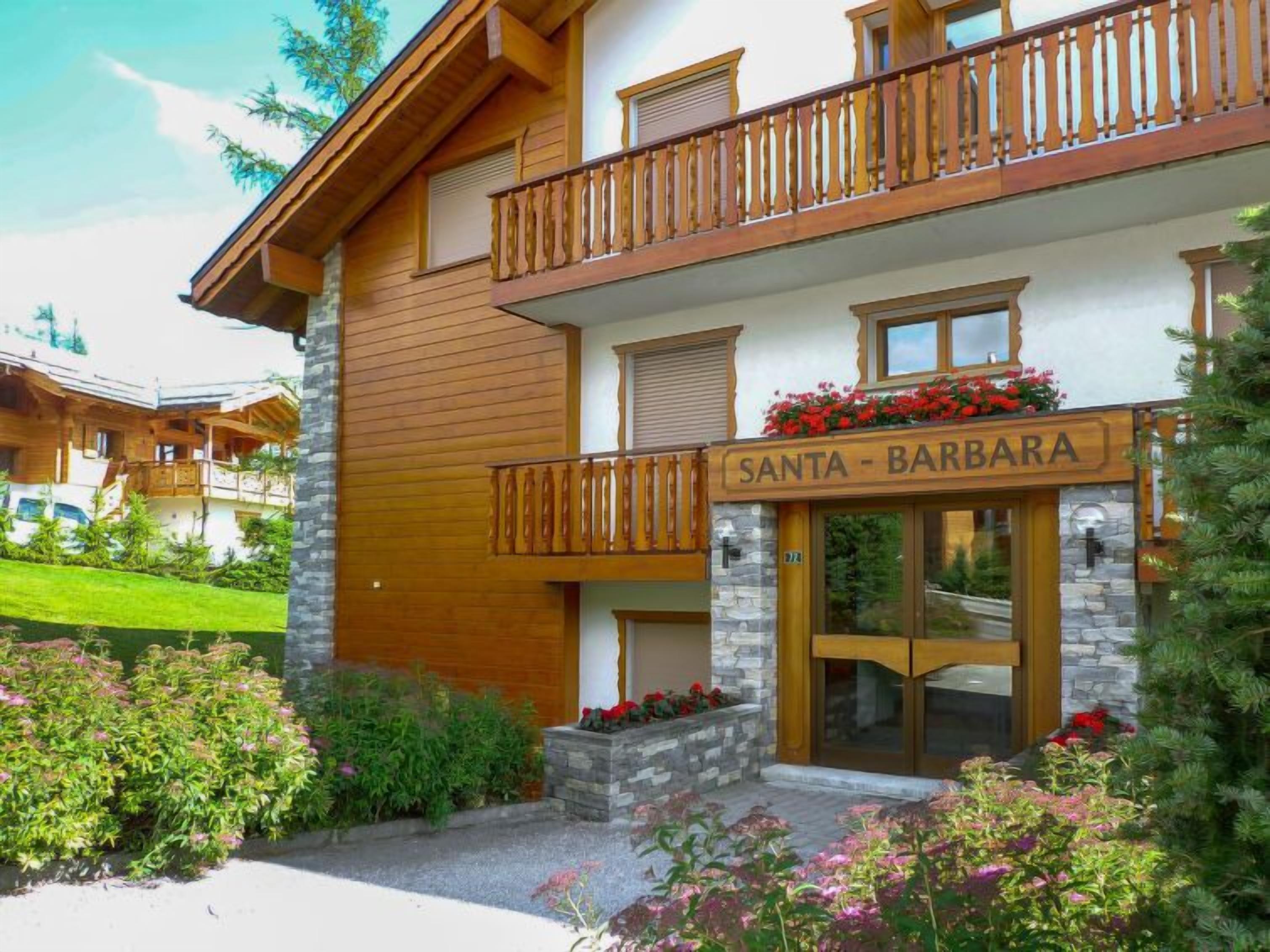Een gebouw met twee verdiepingen, een houten gevel, een balkon met houten spijlen en een bord met de tekst 'SANTA - BARBARA'.