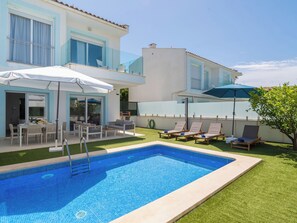 Ein modernes, zweistöckiges Haus mit Swimmingpool, Sitzgelegenheiten im Freien und Meerblick.