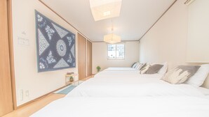 Hotellihuone, jossa on suuri sänky, seinälle kiinnitetty taideteos, ikkuna ja riippuvalaisin.