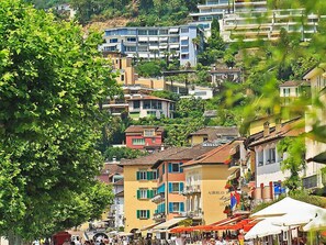A coastal town with colorful buildings, a visible hotel named "Albergo del Sole," and a bustling street scene. - Junior Suite Classic by Interhome (Ascona)