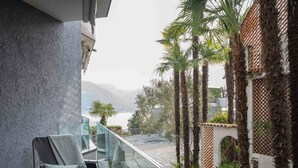 A balcony with a chair, a view of a body of water, and palm trees.