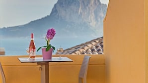 A table with a bottle of wine, a glass, and a pink flower on a balcony overlooking a mountainous landscape. - Montesol by Interhome (Calpe/Calp)