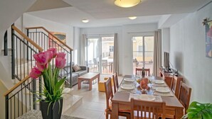 A spacious dining area with a wooden table set for four, a sofa, and a staircase leading to an upper floor. - Montesol by Interhome (Calpe/Calp)