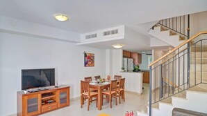 A modern living room with a TV, wooden dining table, and yellow ottomans. - Montesol by Interhome (Calpe/Calp)