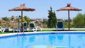 A swimming pool with lounge chairs and thatched umbrellas, surrounded by a fence and greenery. - Montesol by Interhome (Calpe/Calp)