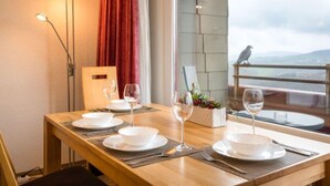 A dining table set with white plates, glasses, and cutlery, a vase with flowers, and a bird on the balcony railing. - Luna (B901) by Interhome (Lahnstein (Koblenz))