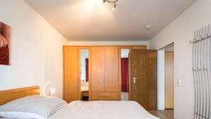 A bedroom with two beds, wooden wardrobes, and a wardrobe with a mirror. - Luna (B901) by Interhome (Lahnstein (Koblenz))