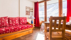Een gezellige kamer met een houten bank, een eettafel en uitzicht op besneeuwde bergen.