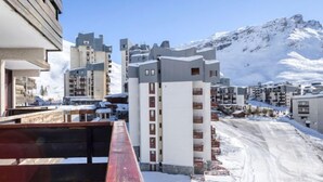 Een bergstad bedekt met sneeuw, met moderne gebouwen, waaronder een opvallend wit gebouw met balkons.