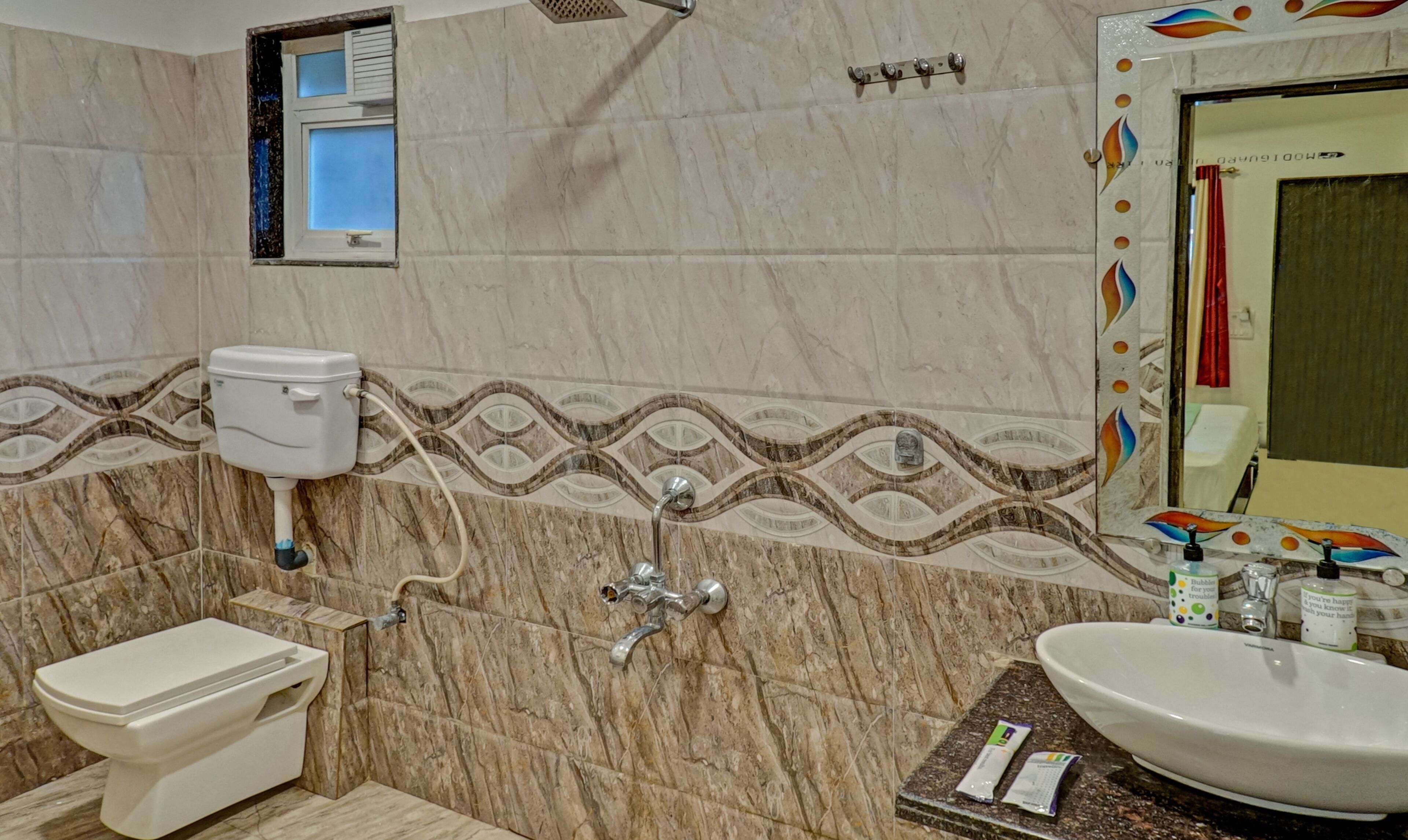 Et badeværelse med toilet, bidet, vask og brusebad.