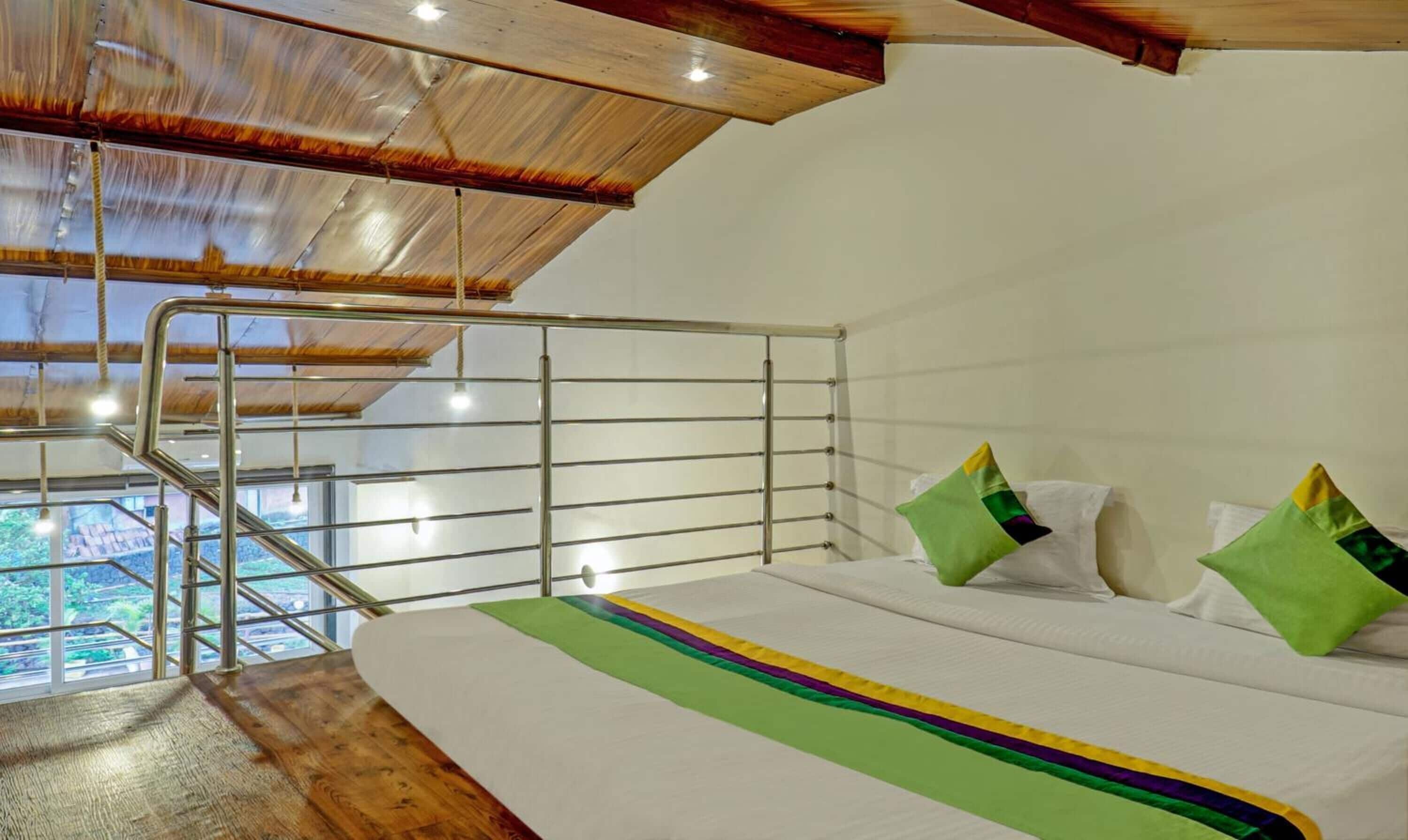 A bedroom with a bed, pillows, a view of greenery, and a wooden ceiling.