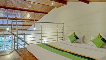 A bedroom with a bed, pillows, a view of greenery, and a wooden ceiling.
