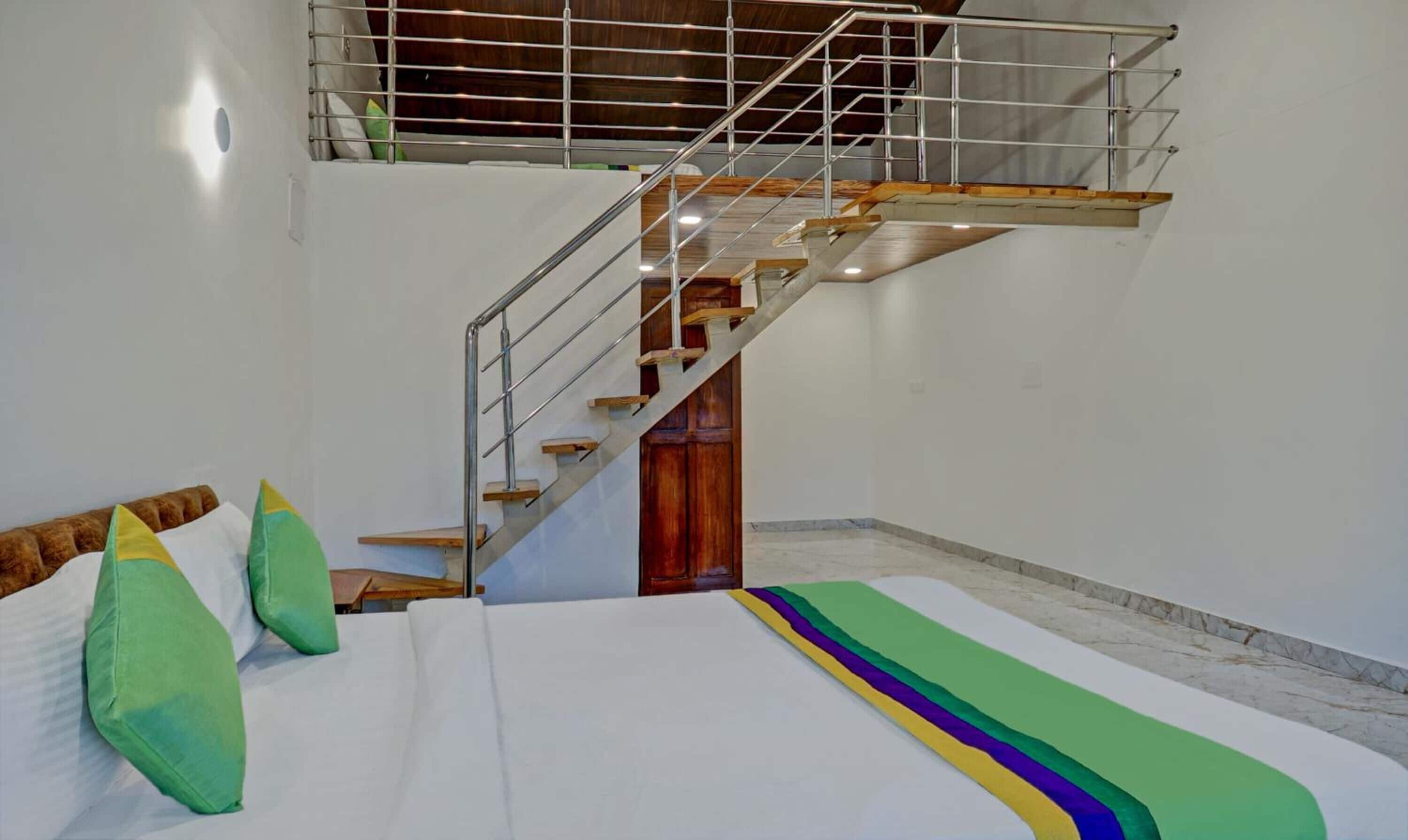 A bedroom with a bed, a wooden staircase, and a view of the sky.