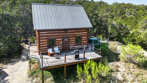 Een blokhut met een metalen dak, een terras met buitenmeubels en een groene hottub.