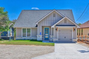 A two-story house with a garage, a front porch, and a well-maintained lawn. - Canyon Lake Getaway | Private Hot Tub, Fire Pit, Game Room & Near River (Fischer)